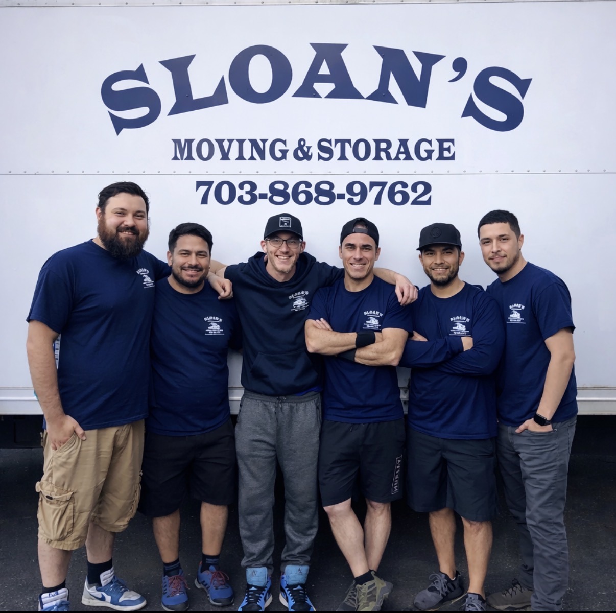 The Sloan's Moving & Storage crew in uniform in front of a branded Sloan's moving truck