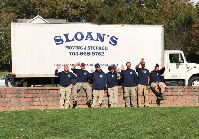 The Sloan's Moving & Storage crew waving in front of a branded Sloan's box truck